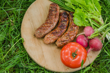Grilled sausage and vegetables on old wooden background. Top view.
