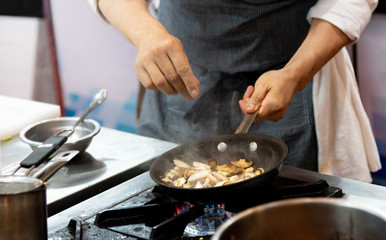 chef frying mushrooms in the kitchen of the restaurant