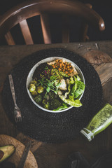 Healthy dinner or lunch setting. Flat-lay of vegan superbowl or Buddha bowl with hummus, vegetables, fresh salad, beans, couscous and avocado and green smoothie on wooden table, top view