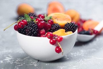 The explosion of different berries. Photo, red currant, black currant, blackberry, apricot on a concrete background.