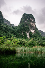 Boat cave tour in Trang An Scenic Landscape formed by karst towers and plants along the river (UNESCO World Heritage Site). It's Halong Bay on land of Vietnam. Ninh Binh province, Vietnam.