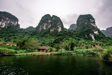 Boat cave tour in Trang An Scenic Landscape formed by karst towers and plants along the river (UNESCO World Heritage Site). It's Halong Bay on land of Vietnam. Ninh Binh province, Vietnam.