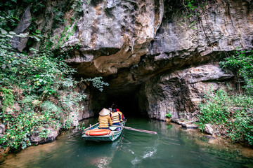 Naklejka na ściany i meble Boat cave tour in Trang An Scenic Landscape formed by karst towers and plants along the river (UNESCO World Heritage Site). It's Halong Bay on land of Vietnam. Ninh Binh province, Vietnam.