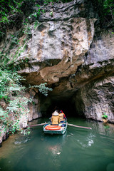 Boat cave tour in Trang An Scenic Landscape formed by karst towers and plants along the river (UNESCO World Heritage Site). It's Halong Bay on land of Vietnam. Ninh Binh province, Vietnam.