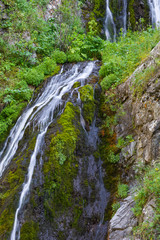Fototapeta na wymiar mountain wooded waterfall among the rocks in summer