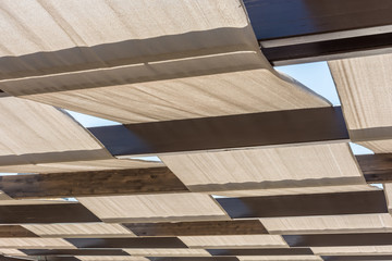 Große Terrassenüberdachung mit Stoffbahnen und Holzbalken als Sonnenschutz