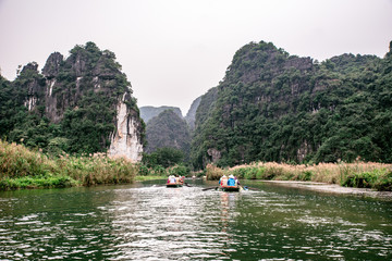 Boat cave tour in Trang An Scenic Landscape formed by karst towers and plants along the river (UNESCO World Heritage Site). It's Halong Bay on land of Vietnam. Ninh Binh province, Vietnam.