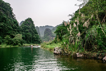 Obraz premium Boat cave tour in Trang An Scenic Landscape formed by karst towers and plants along the river (UNESCO World Heritage Site). It's Halong Bay on land of Vietnam. Ninh Binh province, Vietnam.