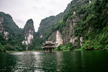 Fototapeta na wymiar Boat cave tour in Trang An Scenic Landscape formed by karst towers and plants along the river (UNESCO World Heritage Site). It's Halong Bay on land of Vietnam. Ninh Binh province, Vietnam.