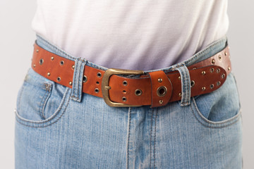 Man standing in blue jeans and brown leather handmade belt, closeup. indoor studio shot, isolated...