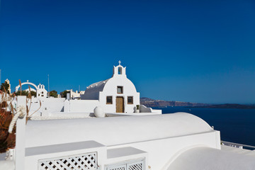 Old white ortodox church in sunny day with blue sky in Oia on Santorini island low view