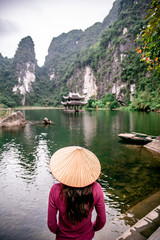 Vietnamese Girl with straw hat in Trang An. It's Halong Bay on land of Vietnam. Ninh Binh province, Vietnam.