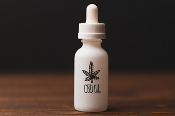 White glass bottle with text CBD Oil and Cannabis or hemp leaf sign