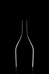 Stylish silhouette of elegant black corked wine bottle reflected and outlined by light on black background