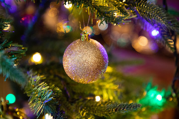 Golden decoration globe on christmas tree close up