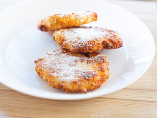 beautiful fried cheesecakes lie on a white plate sprinkled with powdered sugar