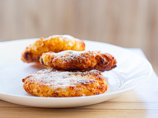 beautiful fried cheesecakes lie on a white plate sprinkled with powdered sugar