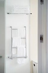 Chrome towel rail in the bathroom. Whites towels on a chromed heated towel rail in the bathroom in hotel room. Modern bathroom heated towel rail.