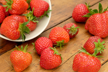 strawberries in a bowl and on a wooden table top