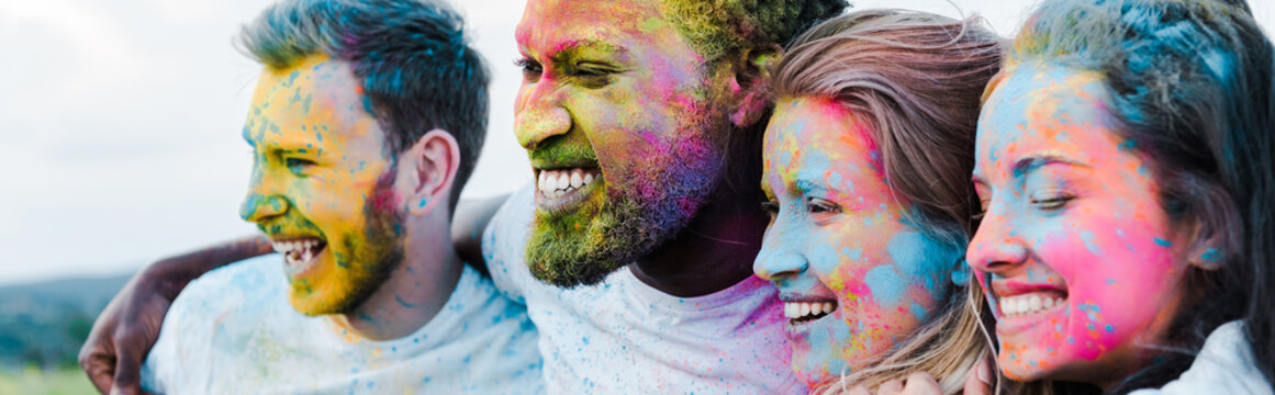 Panoramic shot of woman smiling near multicultural friends with Holi paints on faces