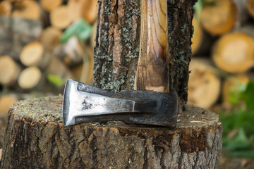Stump and ax. Logging in a country house. Firewood in the background.