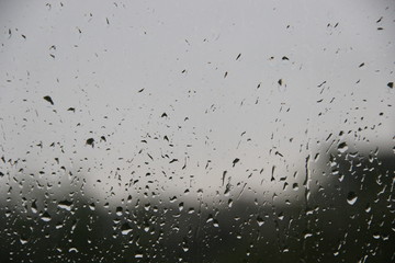 Window with large drops of rain on a gray urban background. The first summer storm, close-up. rain drops on the window glass large detailed, selective focus