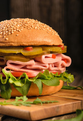 sausage, green salad leaves, cucumber and tomato.Sandwich  on dark background