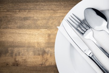 Fork, spoon and knife on plate on wooden background