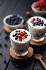 Healthy vegetarian snack. Chia pudding with coconut cream, blueberries and red currants on dark background