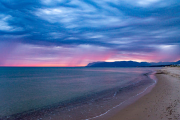Fototapeta na wymiar Scenic gray-blue clouds during sunrise over coastline with sandy beach and clear sea water in Alcamo Marina, small town in Sicily, Italy, summer vacation destination