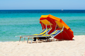 Service on beach, colorful sun bed and parasol for rent on beautiful white sandy beach with crystal clear blue sea water
