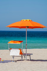 Service on beach, colorful sun bed and parasol for rent on beautiful white sandy beach with crystal clear blue sea water