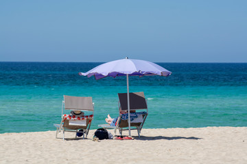 Service on beach, colorful sun bed and parasol for rent on beautiful white sandy beach with crystal...