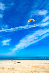 Watersport on vacation, kitesurfer is ready for action on sandy beach with blue sea water