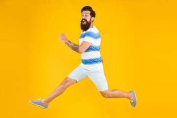 Fototapeta na wymiar Hurry up. Summer vacation. Man bearded hipster with mustache long beard running yellow background. Guy dressed striped shirt on summer vacation. Barbershop concept. Summer style. Sale and discount