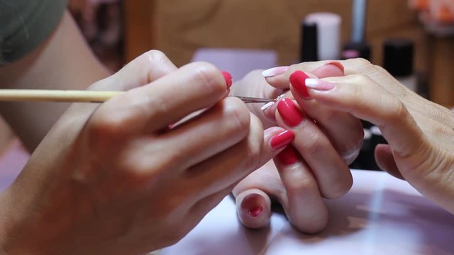 Painting nails. The manicurist smears the nail with glue and applies rhinestones with a special tool. Beautiful female hands and thin fingers in the frame. Female beauty concept.