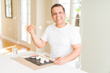 Middle age man eating asian dim sum using chopsticks at home