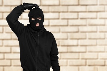 Thief in black balaclava and clothes on background