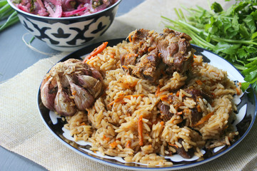 The concept of Oriental cuisine. Homemade Uzbek lamb pilaf is served on a round platter.  Copy space.