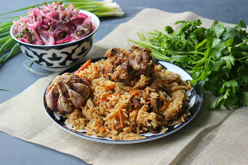 The concept of Oriental cuisine. Homemade Uzbek lamb pilaf is served on a round platter.  Copy space.