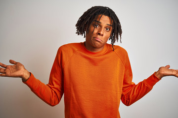 Afro american man with dreadlocks wearing orange sweater over isolated white background clueless...