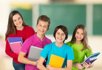 Sad little schoolgirl in classroom on chalkboard background