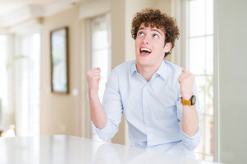 Young business man with curly read head celebrating surprised and amazed for success with arms...