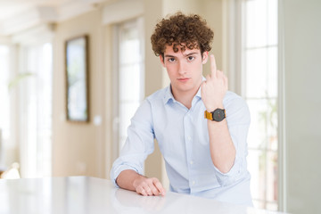 Young business man with curly read head Showing middle finger, impolite and rude fuck off expression