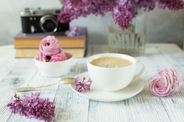 Bouquet of lilacs, cup of coffee, homemade marshmallow and stack of books Retro camera Selective focus