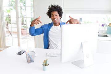 Fototapeta premium African American man working using computer looking confident with smile on face, pointing oneself with fingers proud and happy.