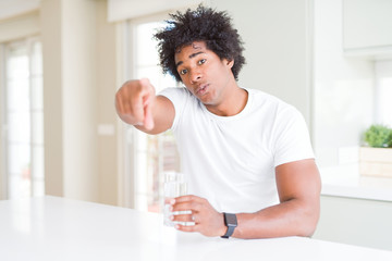 African American man drinking a glass of water at home pointing with finger to the camera and to you, hand sign, positive and confident gesture from the front