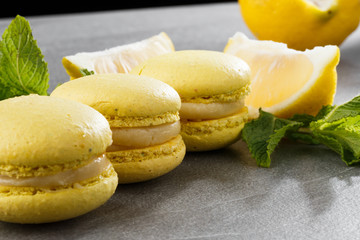 French macaroons isolated. Selective focus. Beautiful yellow macaroons with lemon and mint on gray stone background. Stylish arrangement sweet. Flat lay, top view. Macro photo.