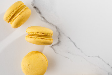 French macaroons isolated. Selective focus. Beautiful yellow macaroons on marble background. Stylish arrangement sweet. Flat lay, top view. Macro photo. With copy space.