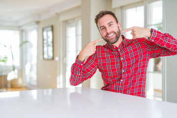 Handsome man wearing colorful shirt smiling confident showing and pointing with fingers teeth and mouth. Health concept.